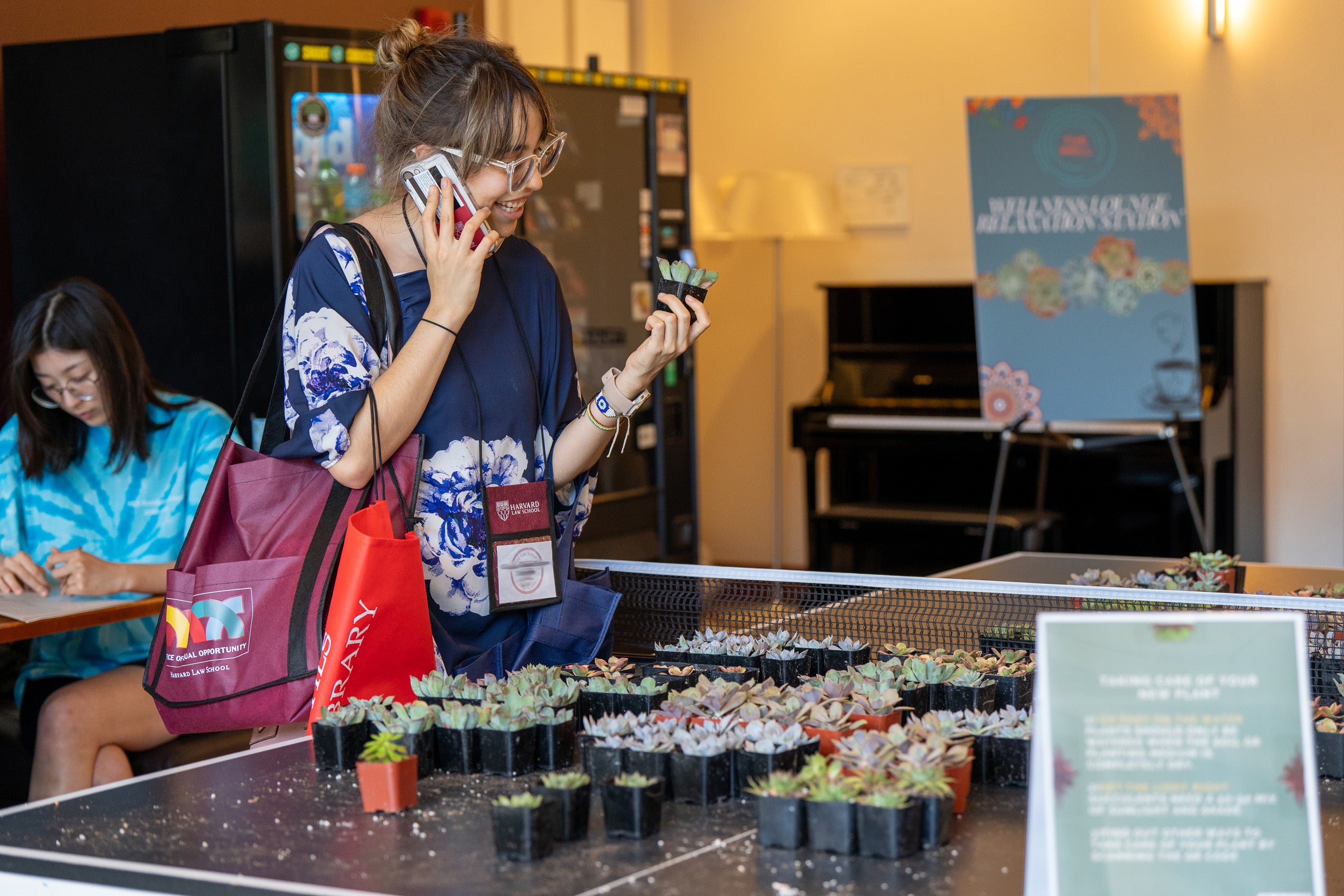 A woman holds a small plant that they picked up from a table during orientation.