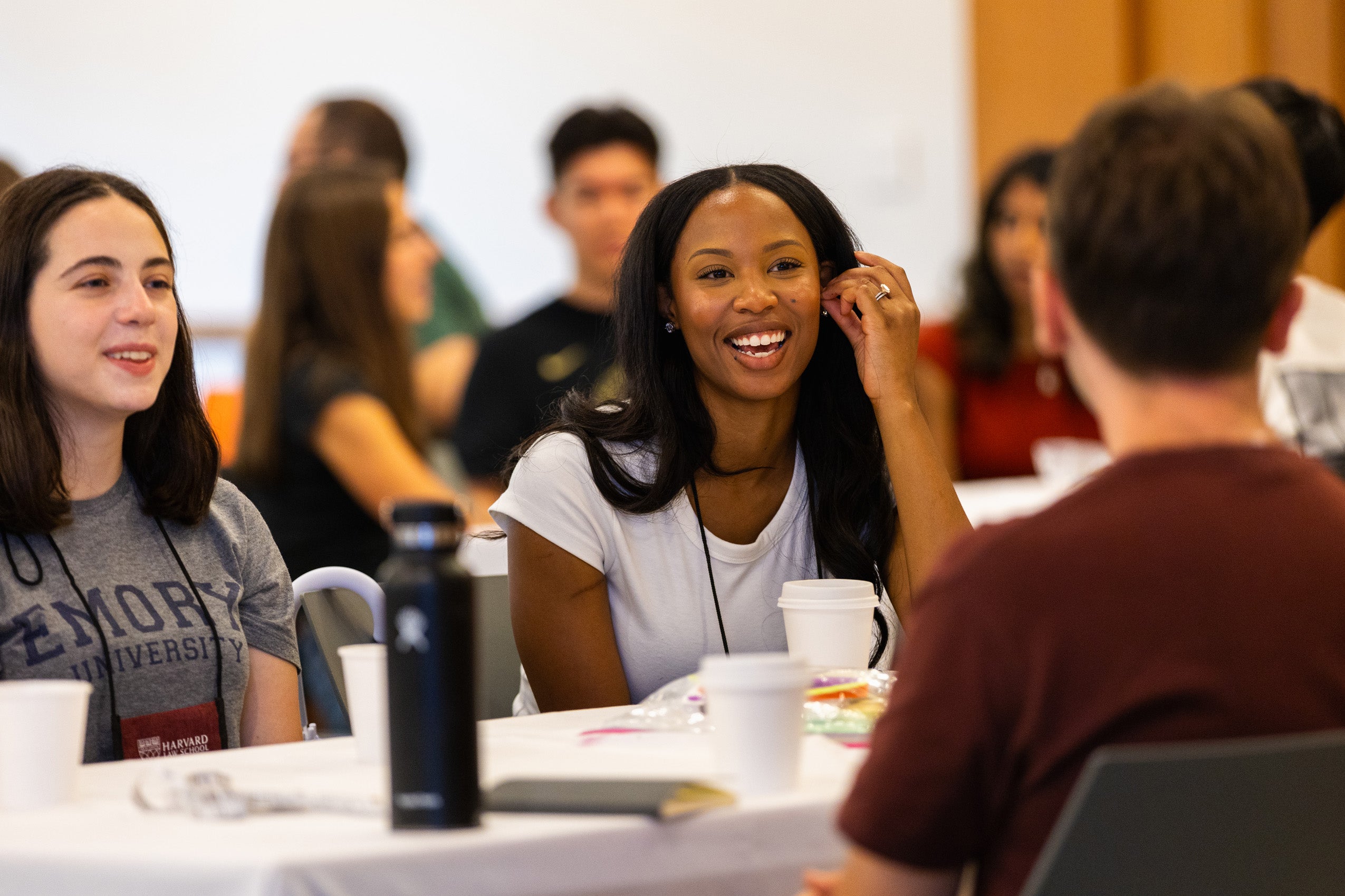 A women smiles while sitting at a table with other students.