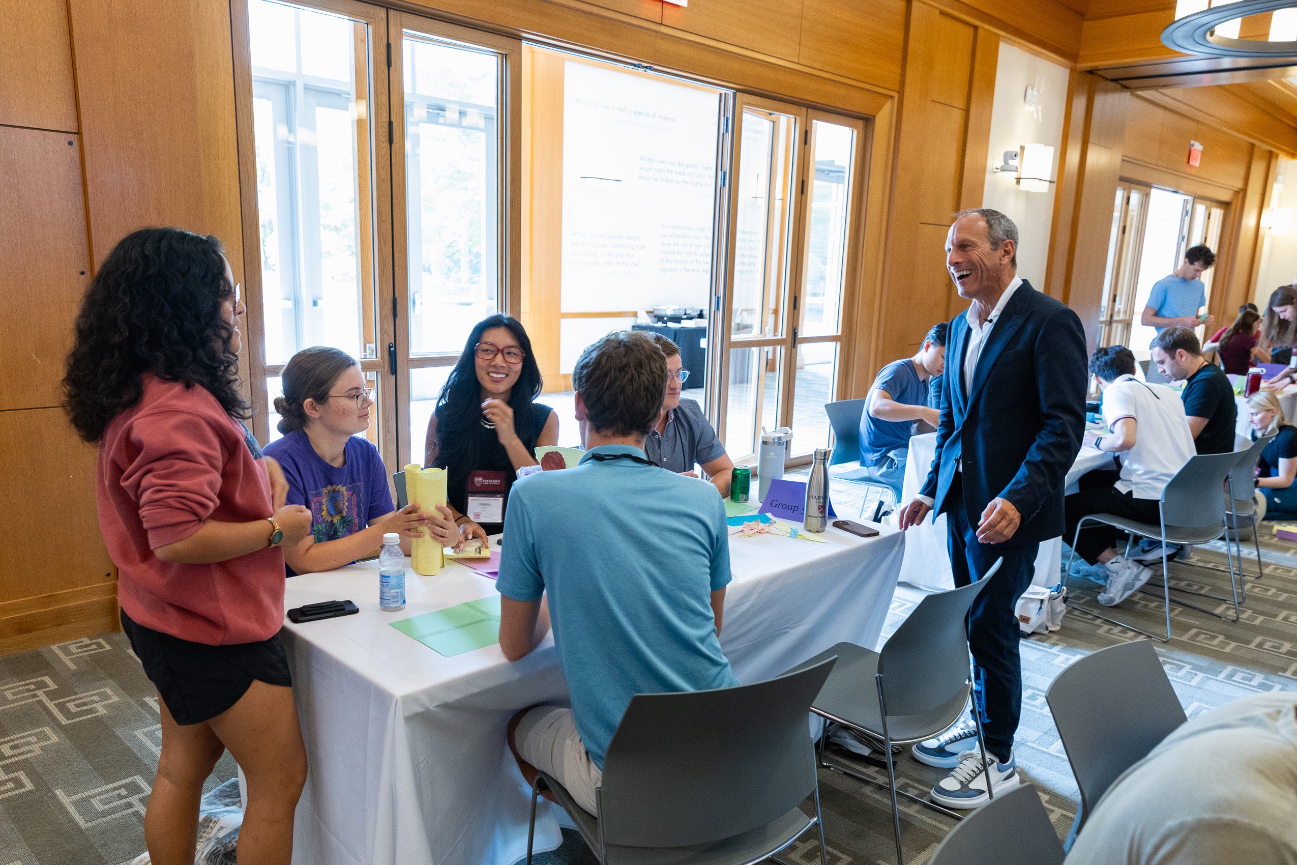 Professor Westfahl chats with students sitting around a table during a team building activity.