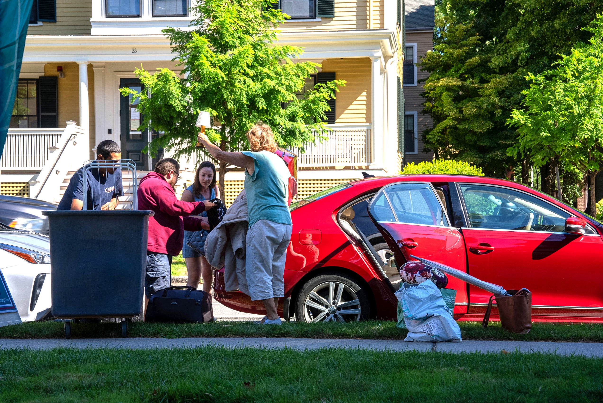 A family unloads a red car on move in day