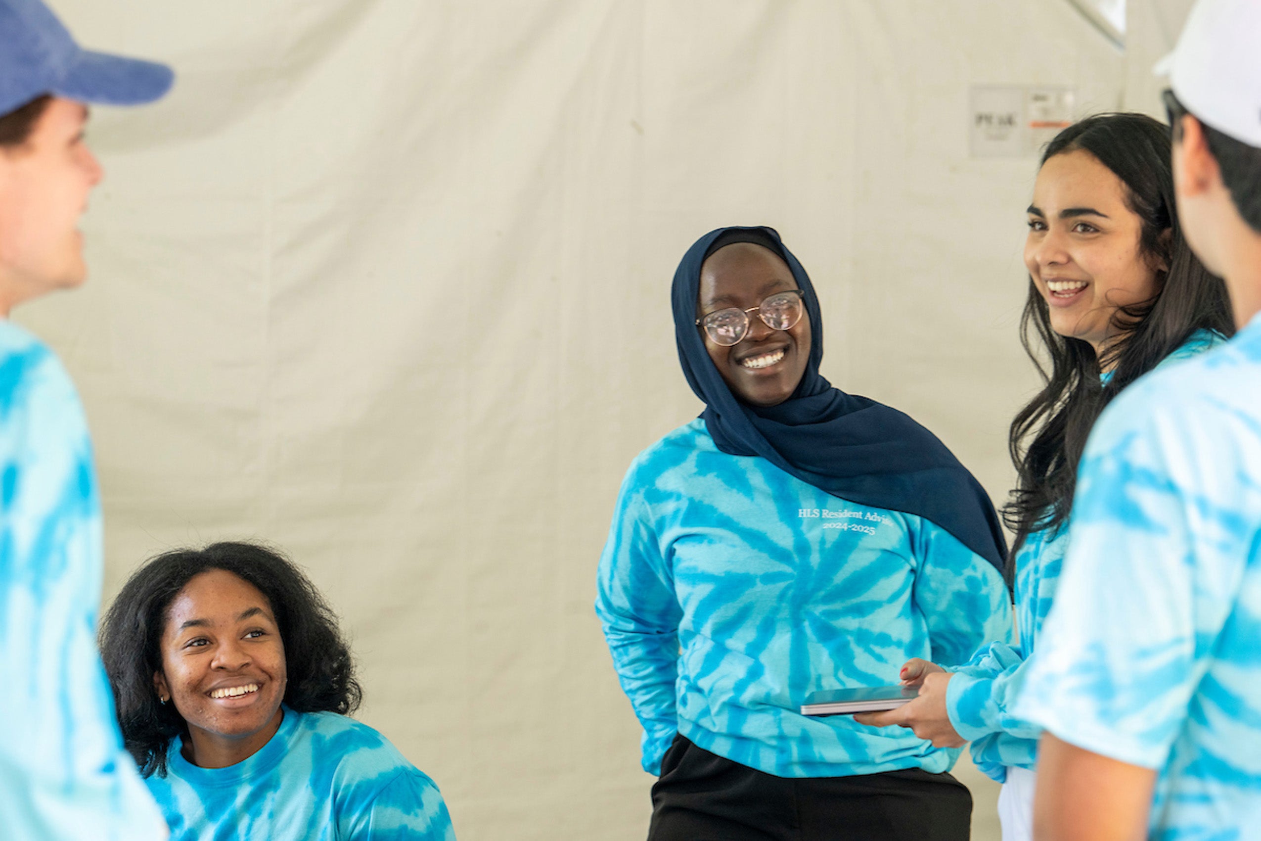 Students wearing blue tie dyed shirts gather during move in day share a light moment