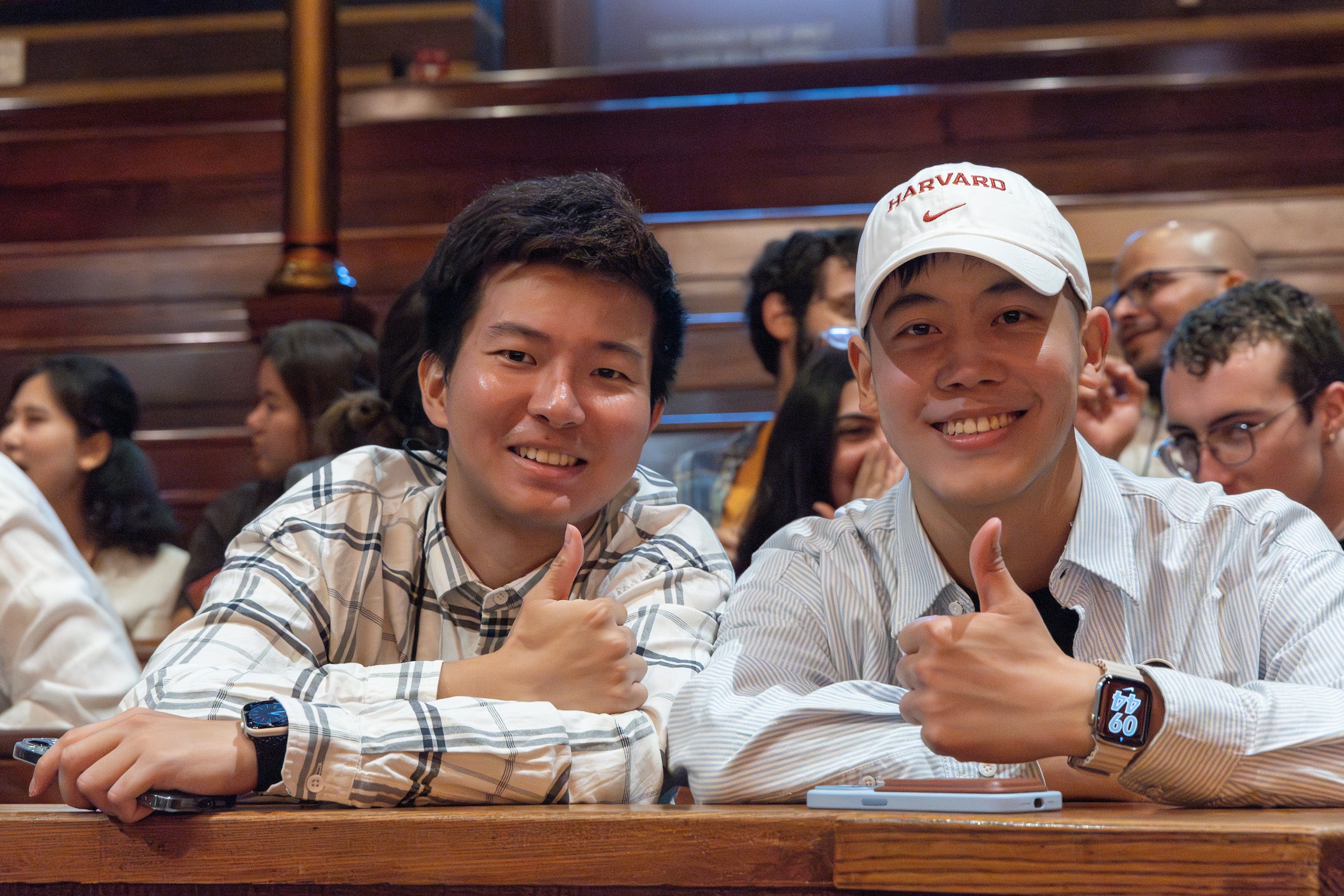 Two students give a a thumbs up at an orientation event in Sanders Theater