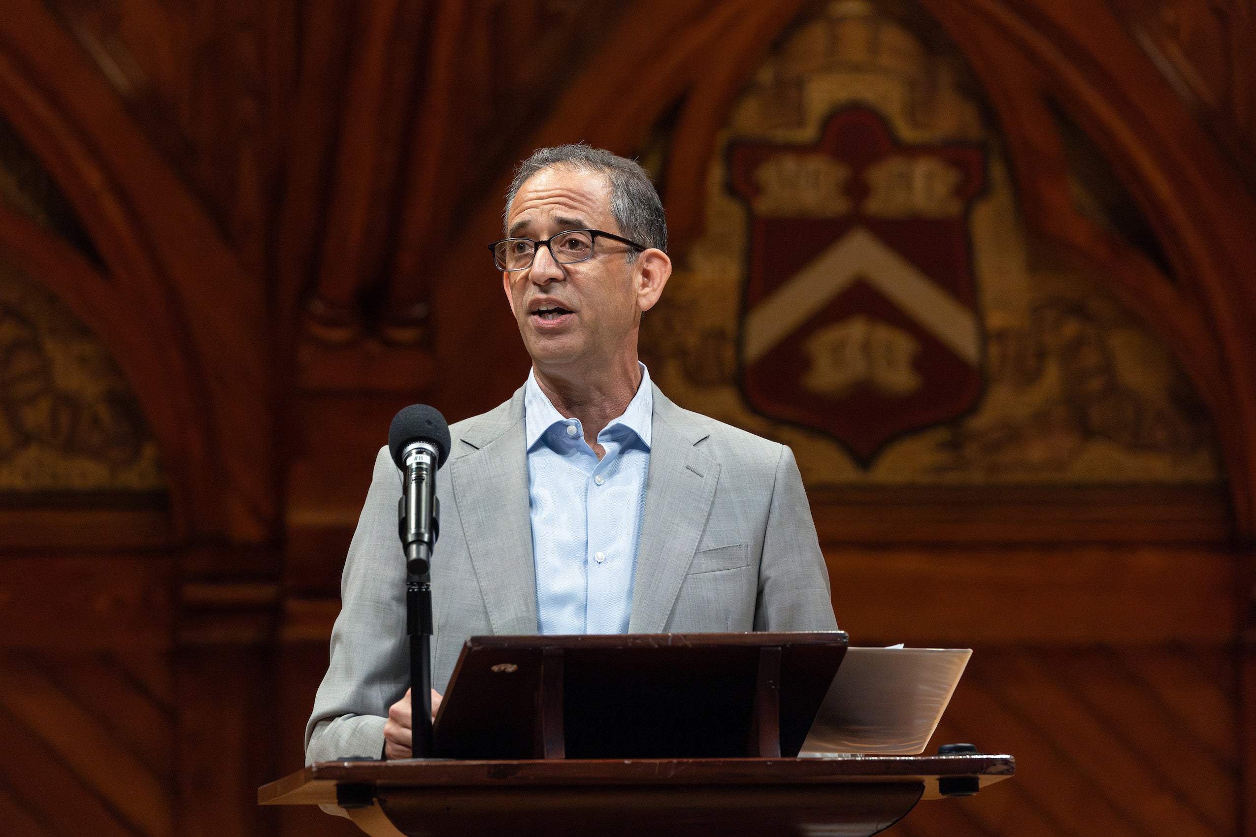 Dean Goldberg delivers remarks from a podium on the stage of Sanders Theater.