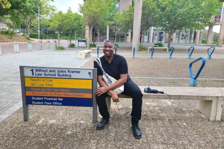 A student sits on a bench on a university campus.
