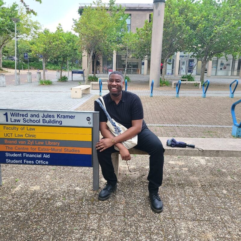 A student sits on a bench on a university campus.