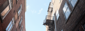 a blue sky between two brick apartment buildings