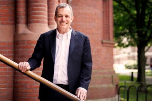 A portrait of Dean Manning in front of a red brick building in Harvard Yard.