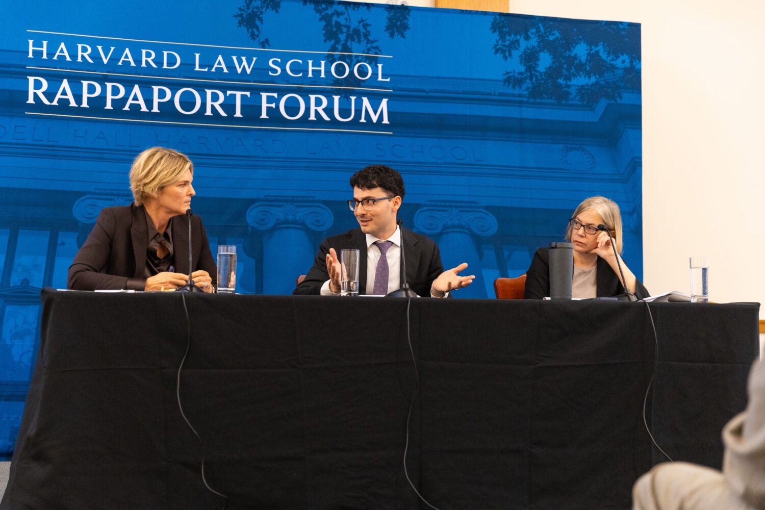 Three people seated speak on a panel at an event.