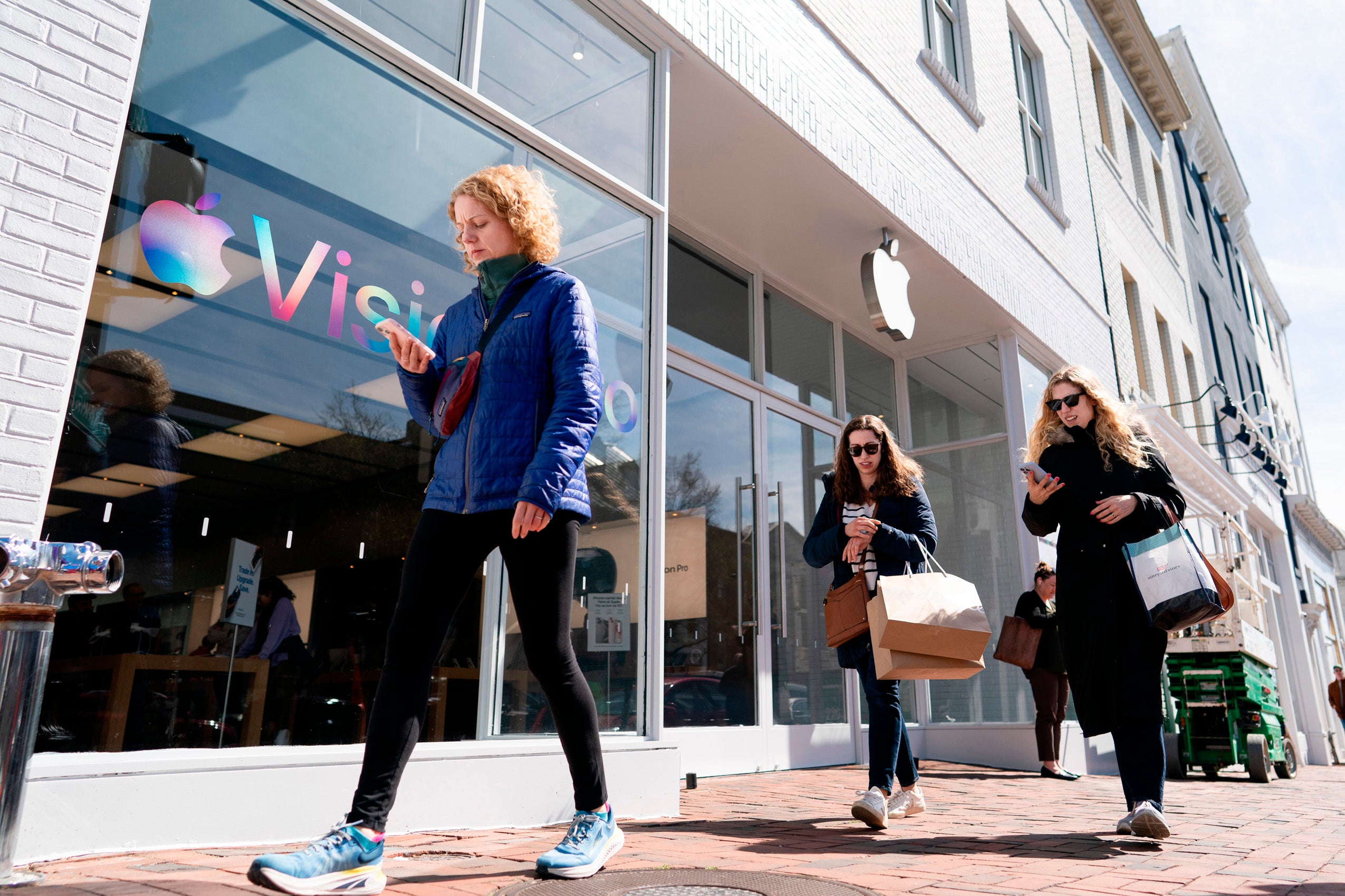 A candid shot of people walking past an Apple Store