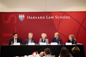 A panel of six people in front of a Harvard Law School crimson backdrop