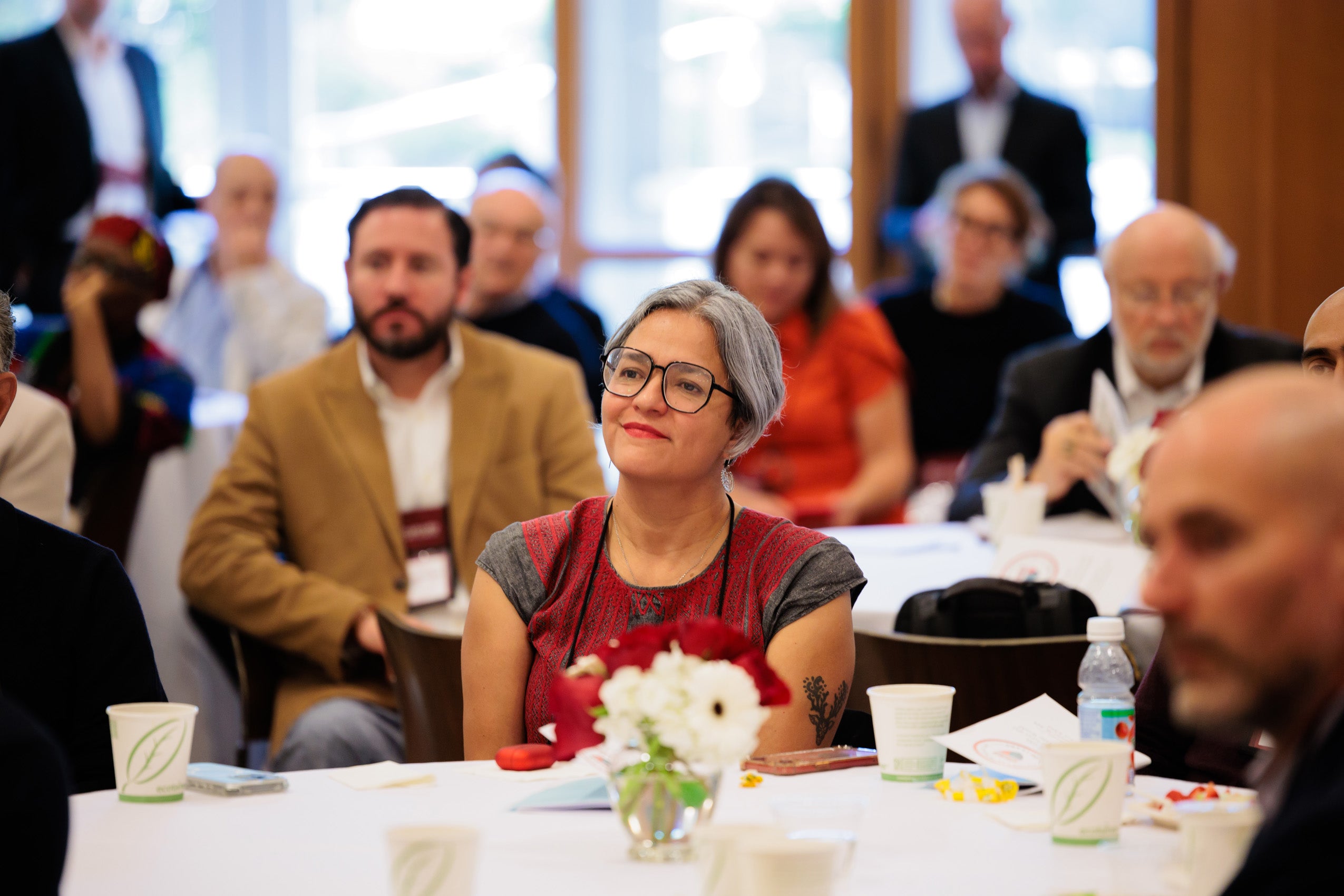 A woman sitting at a table listens to a talk