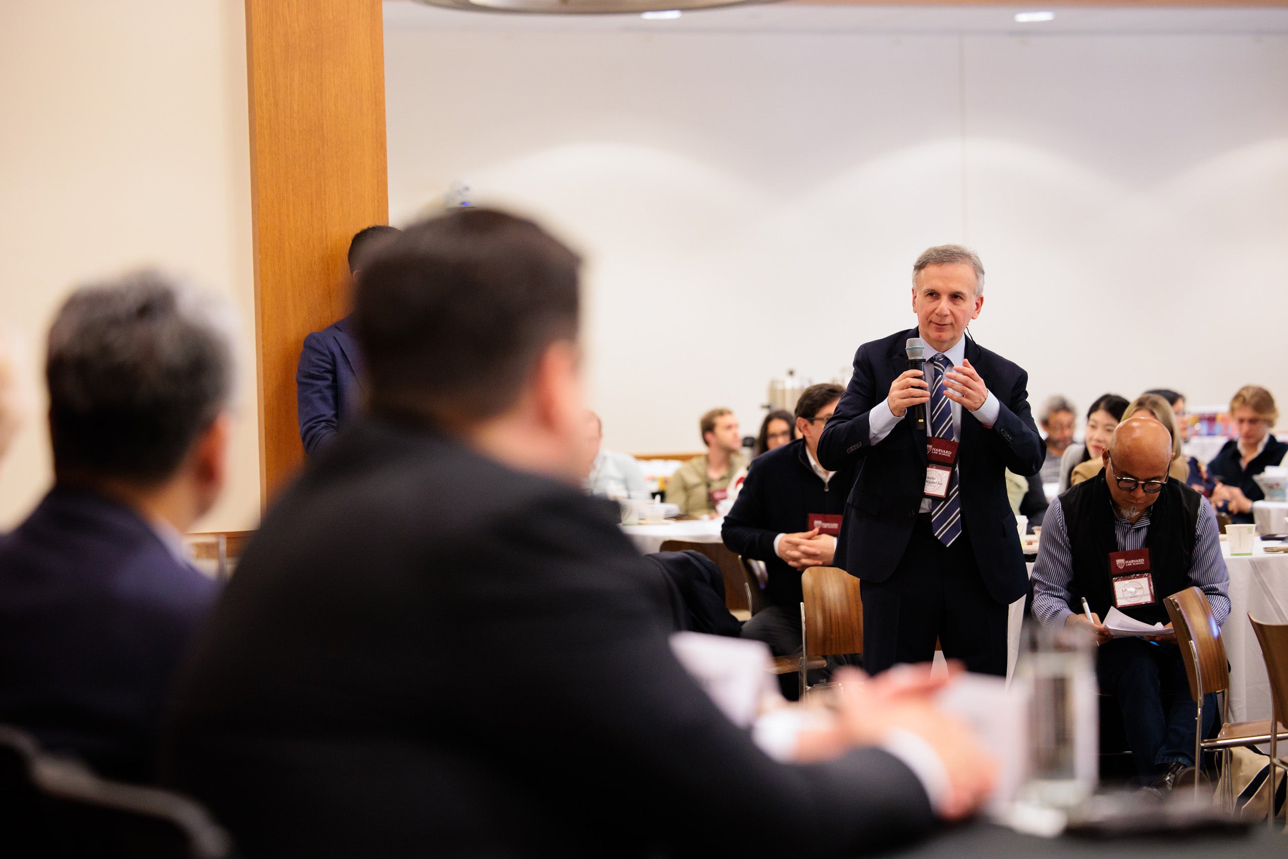 A man in the audience asks a question of the panelists in the front of the room