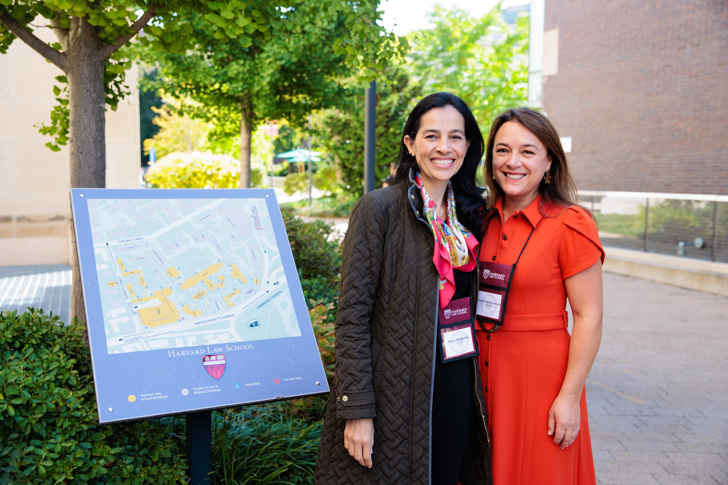 Two women post for a photo near a Harvard Law School sign