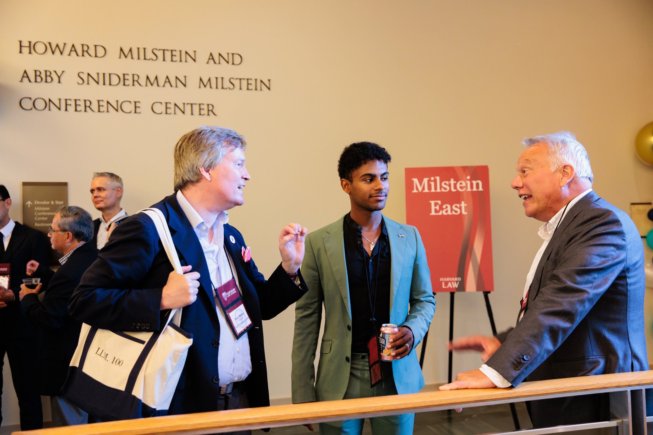 Three men chat in a hallway at an event.