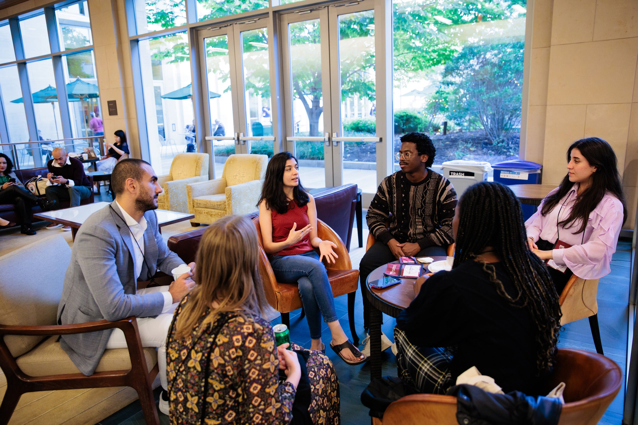 A small group of people sitting around some comfortable seating talking in a lounge area