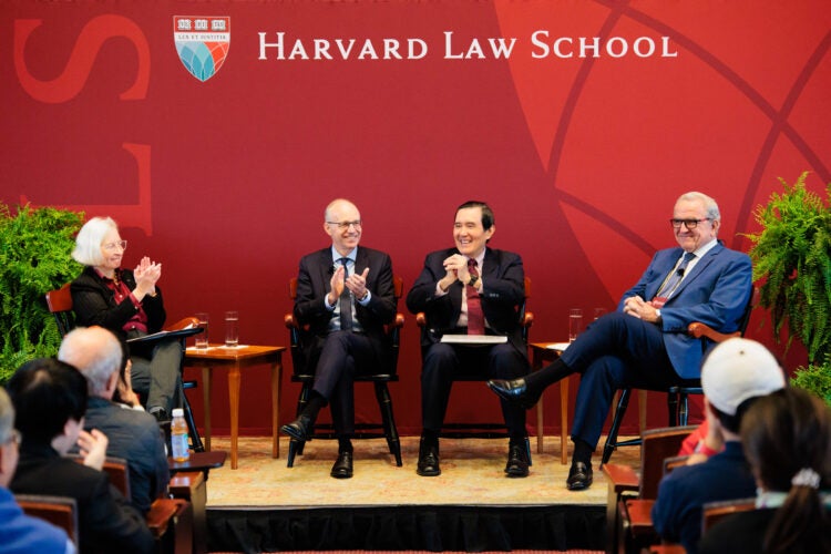 A woman and two men sitting in chairs on a stage in front of an audience