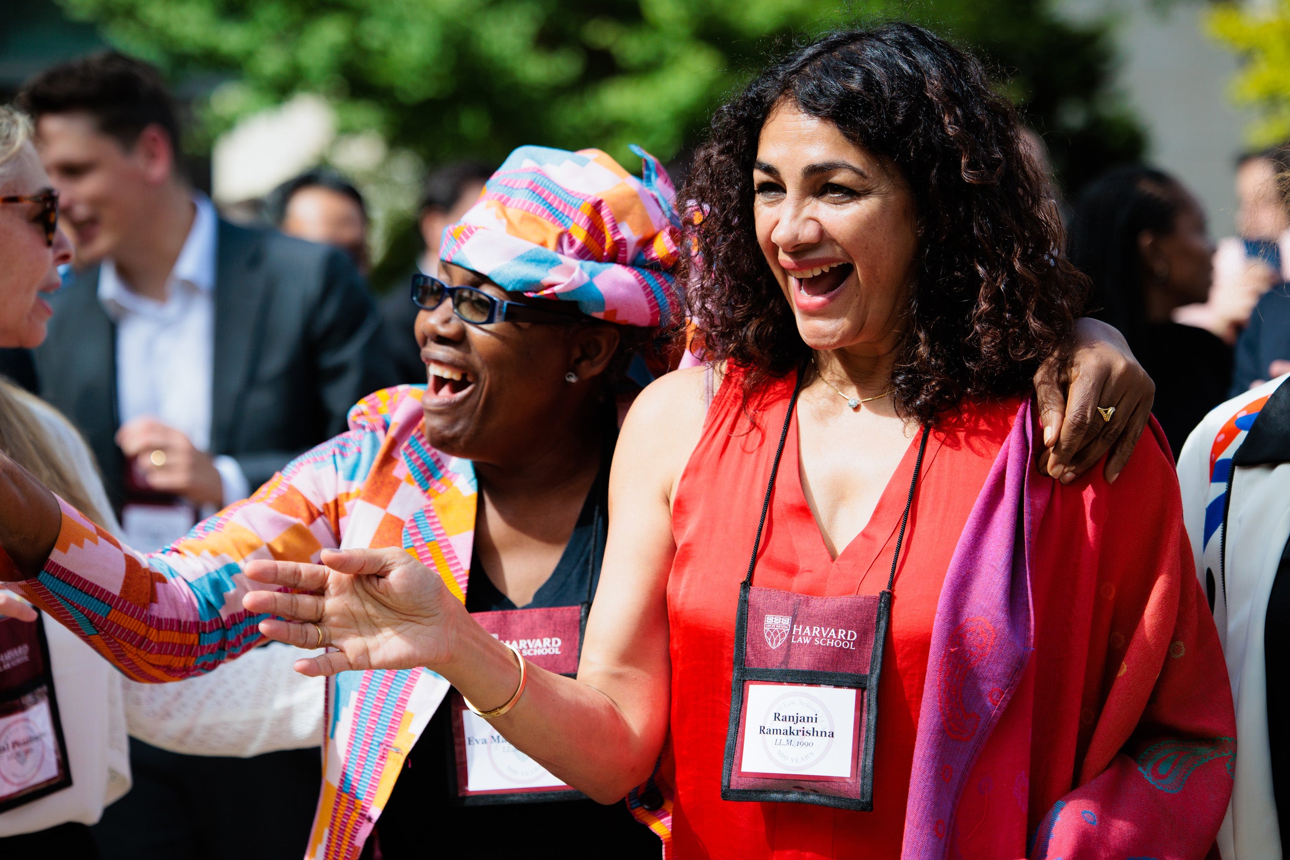 Two women share a light moment among a crowd.