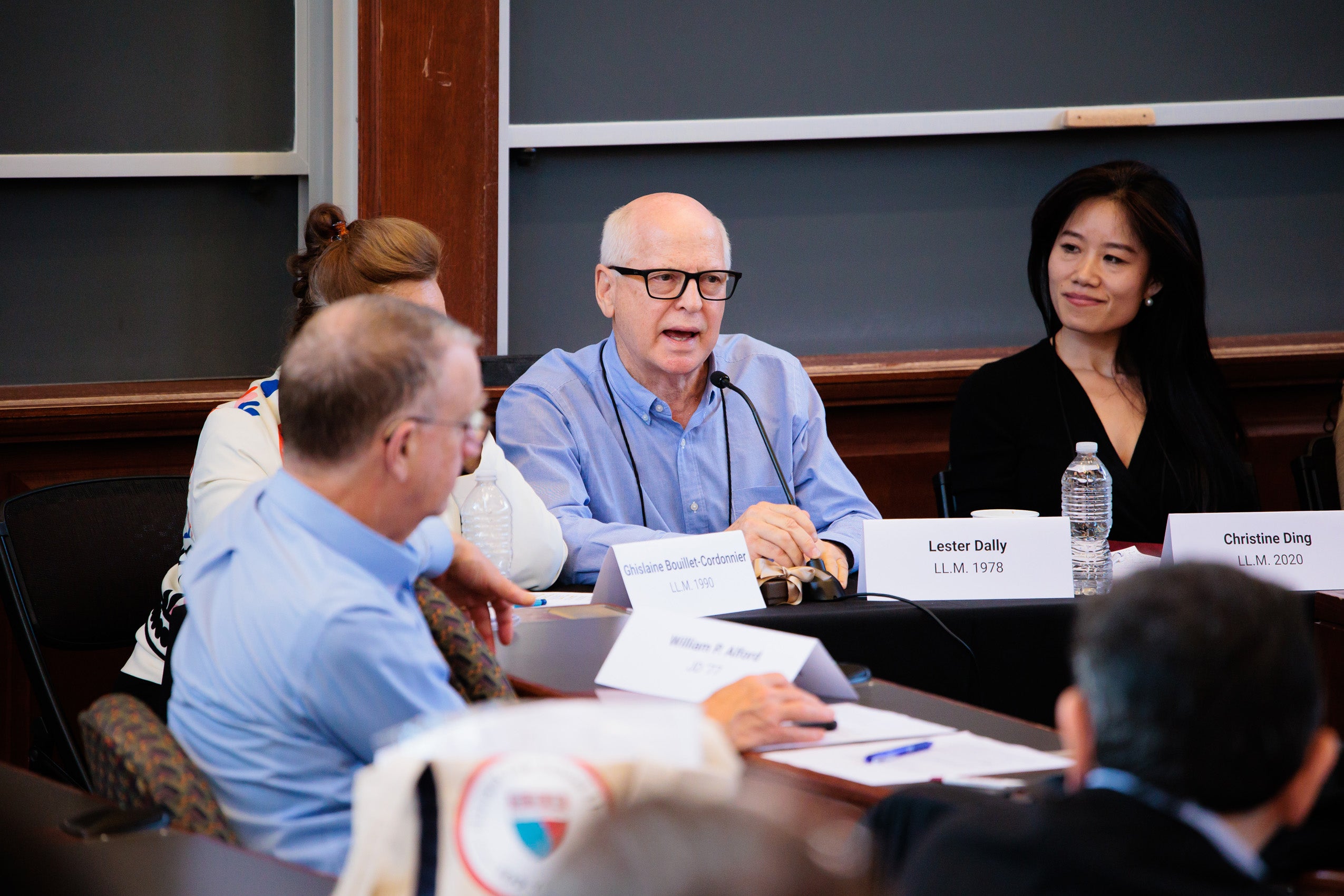 A man speaks on a panel with others looking on.