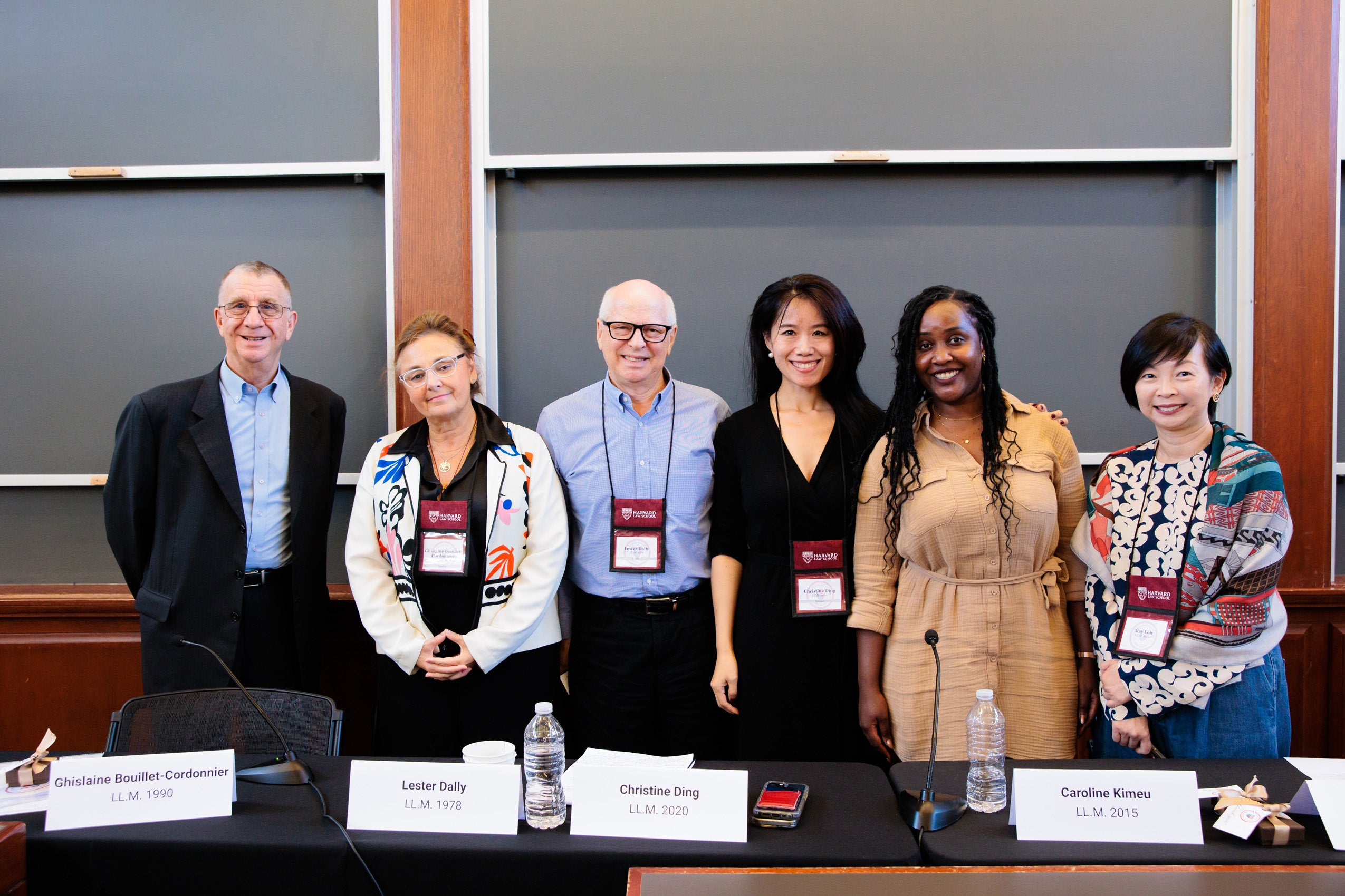 Six people pose for a photo in a classroom.