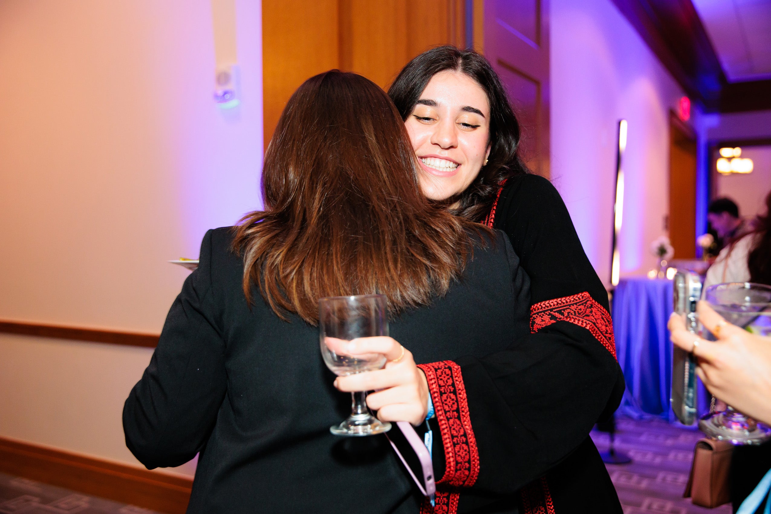 Two women greet each other with a hug at an event
