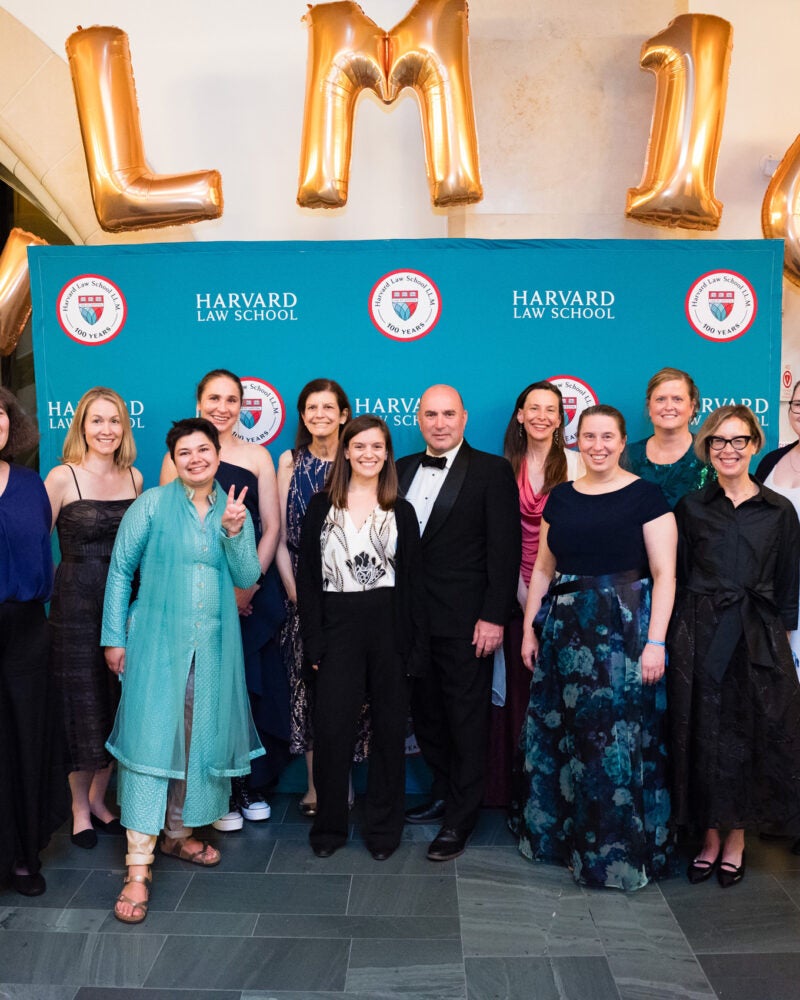 A group photo of the graduate program staff under the LL.M. 100 balloons.