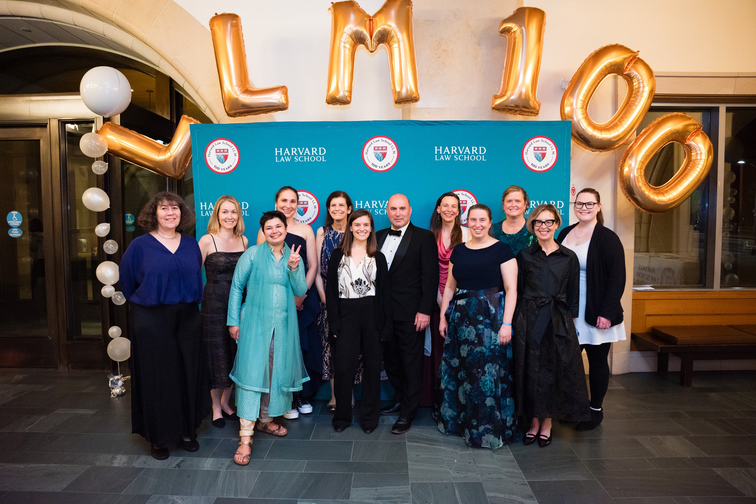 A group photo of the graduate program staff under the LL.M. 100 balloons.