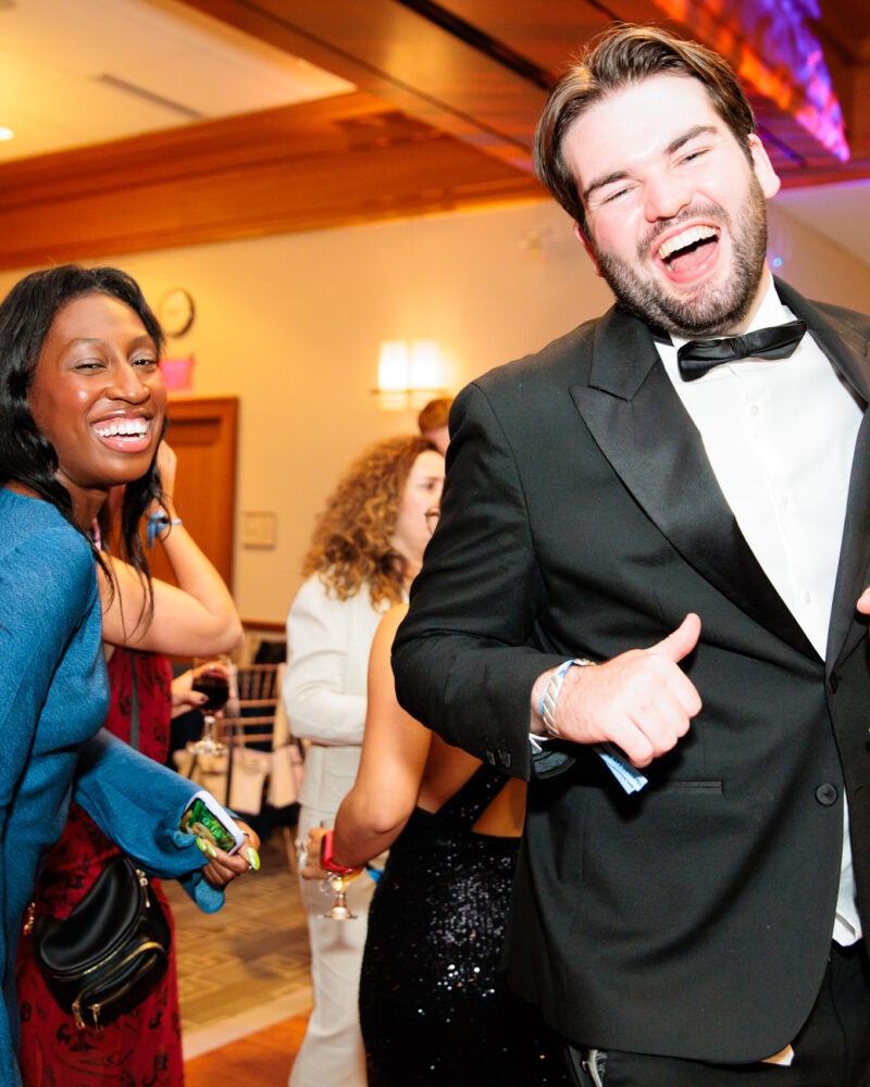 A man in a tuxedo and a woman in a blue dress enjoying the dance floor at a party