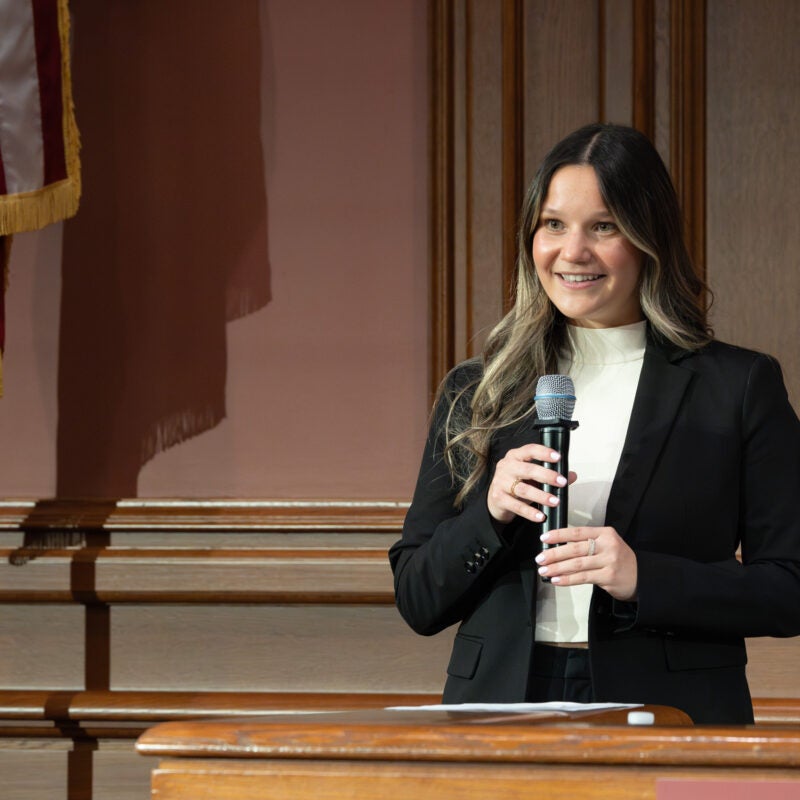 A woman standing in the front of a room holding a microphone