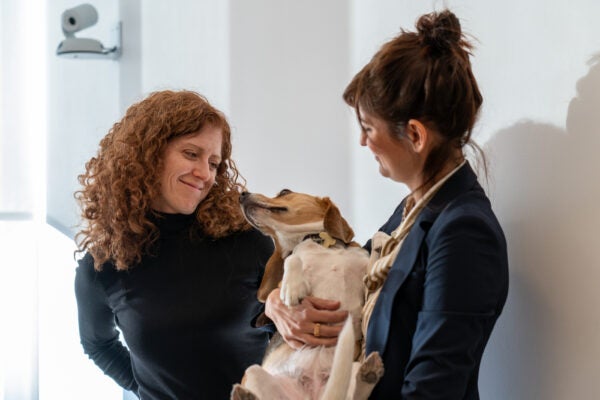 two women smile at a beagle
