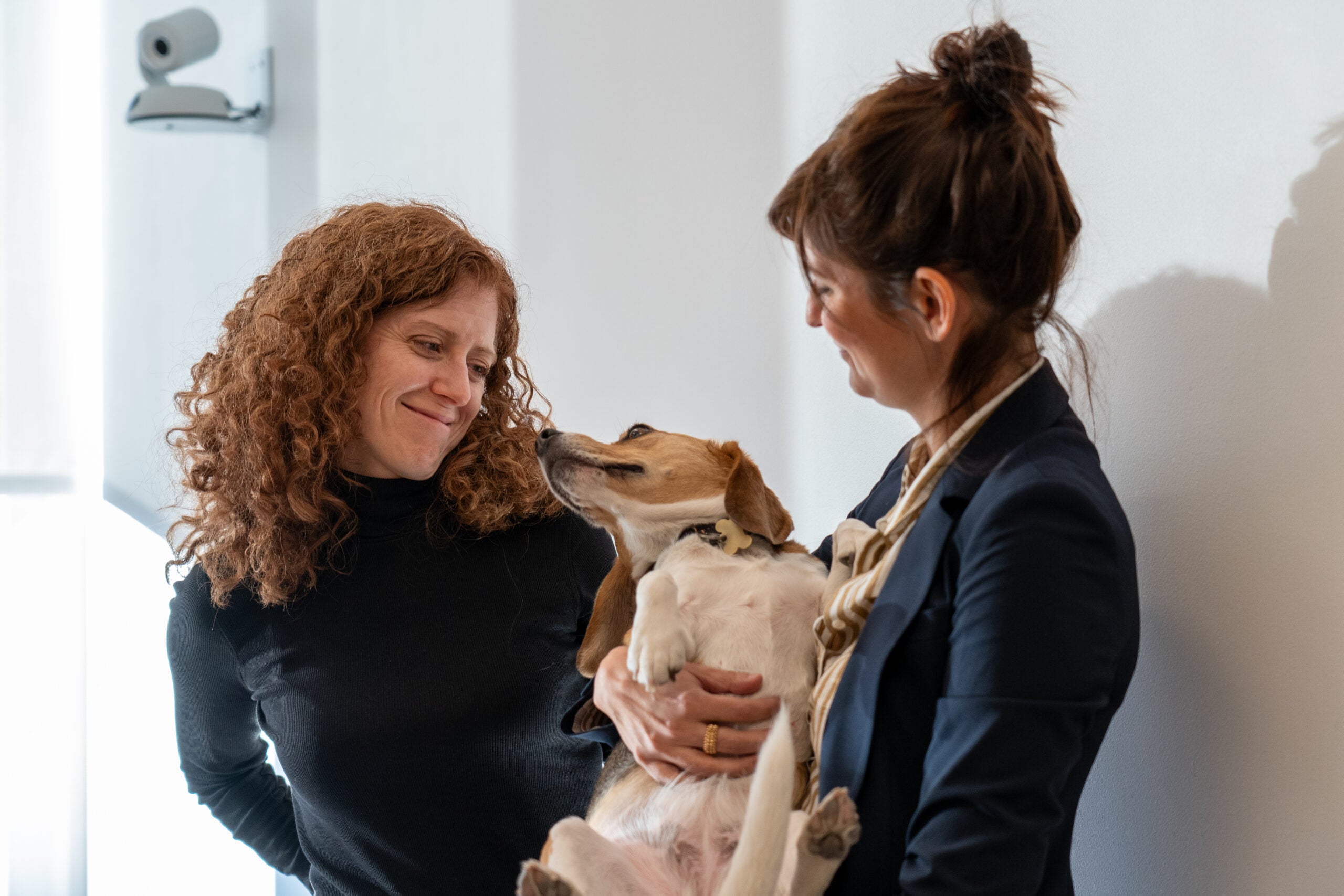 two women smile at a beagle