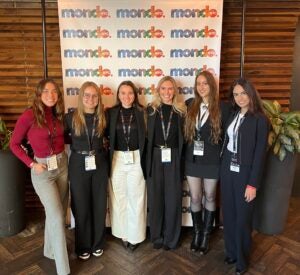 Six RAP students stand in front of a Mondo conference banner