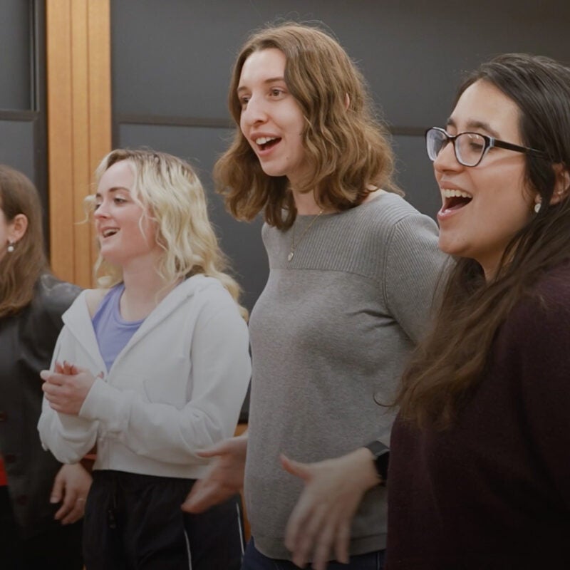 Four students sing in a classroom.