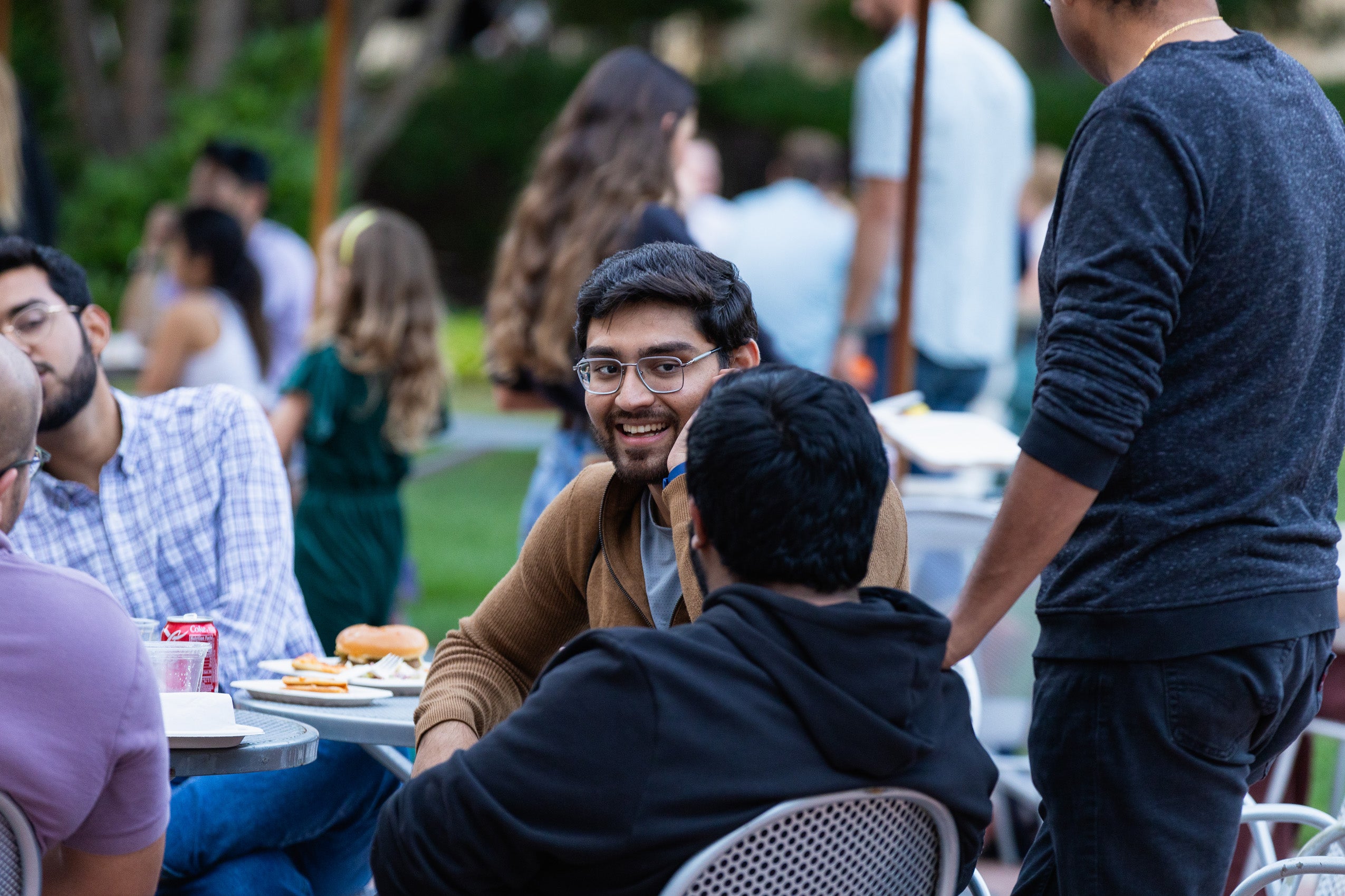Students outside chat at a table at an event.
