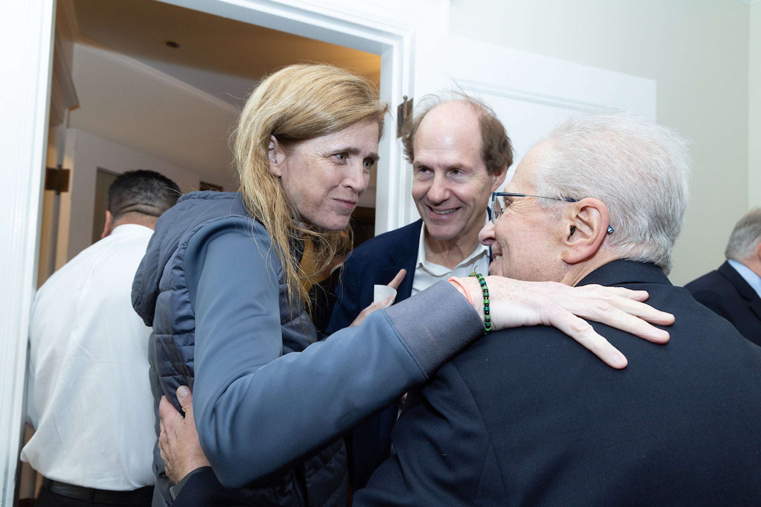 Three people greet each other at an event.