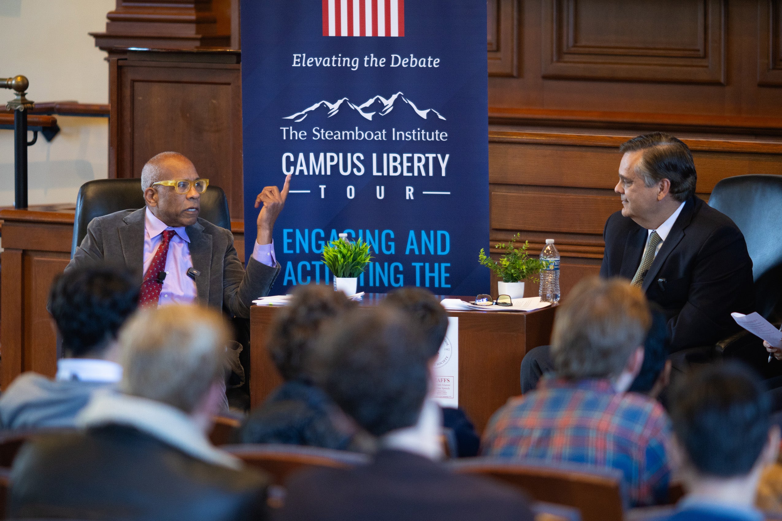 Two people sitting at the front of an audience discuss a topic.