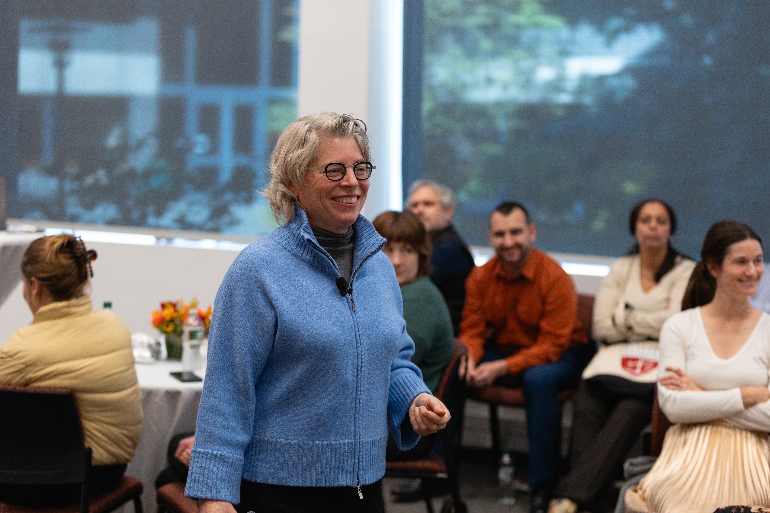 A woman stands in the middle of the room as she gives a talk to those present.