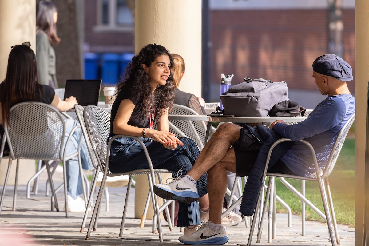 Two students talking at a table outside