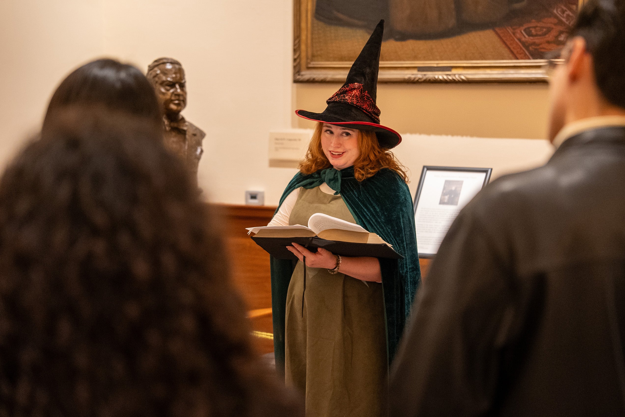 A woman wearing a witch hat on a haunted tour of a library