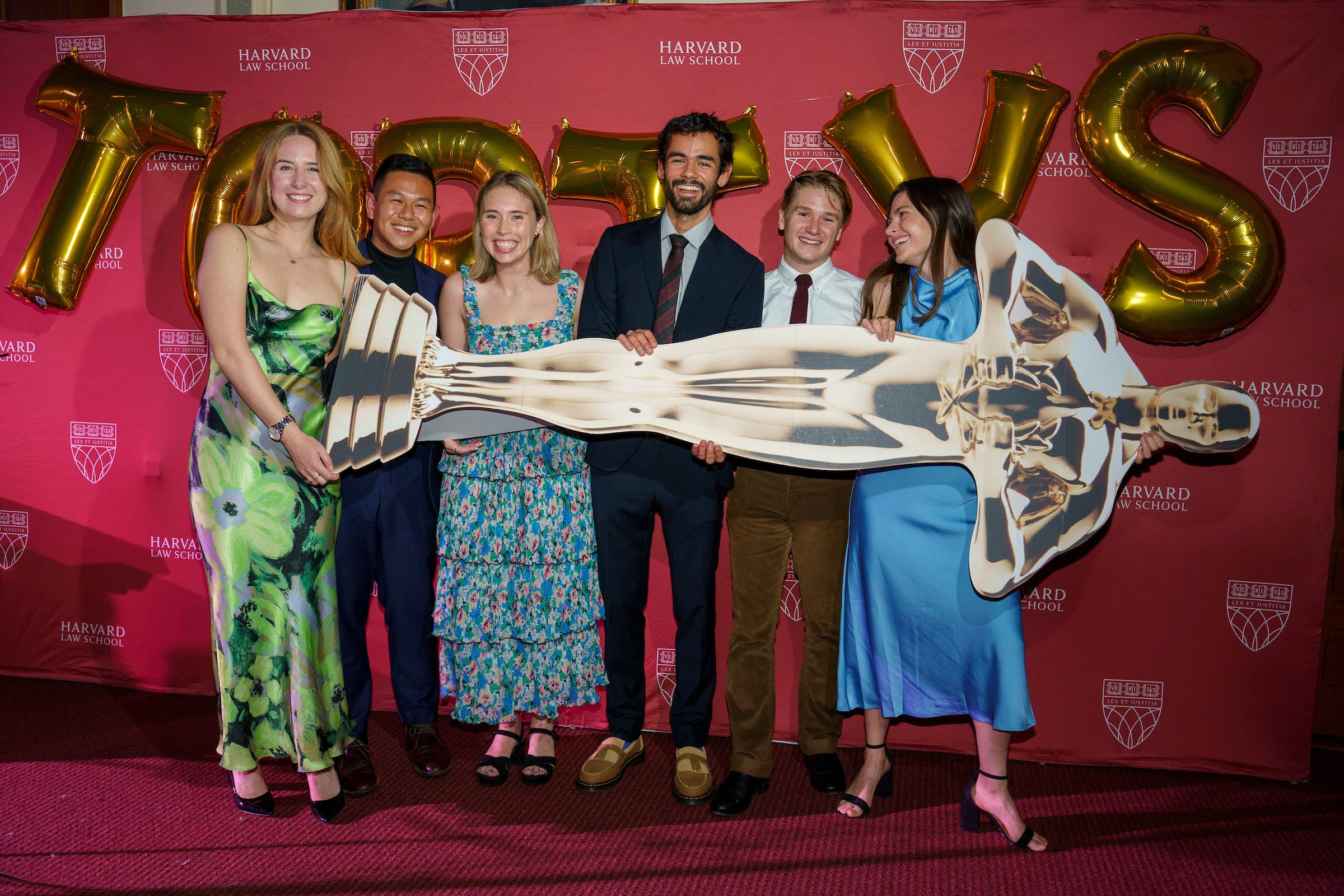 Group of six students hold a life-sized cardboard cutout of an award.