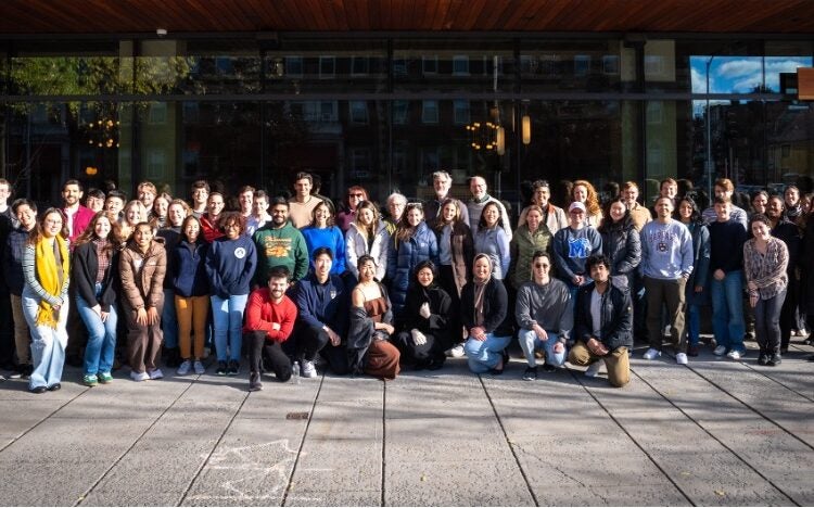 a group of students and instructors pose outside a glass building