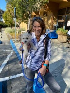 a woman smiles while holding a small dog