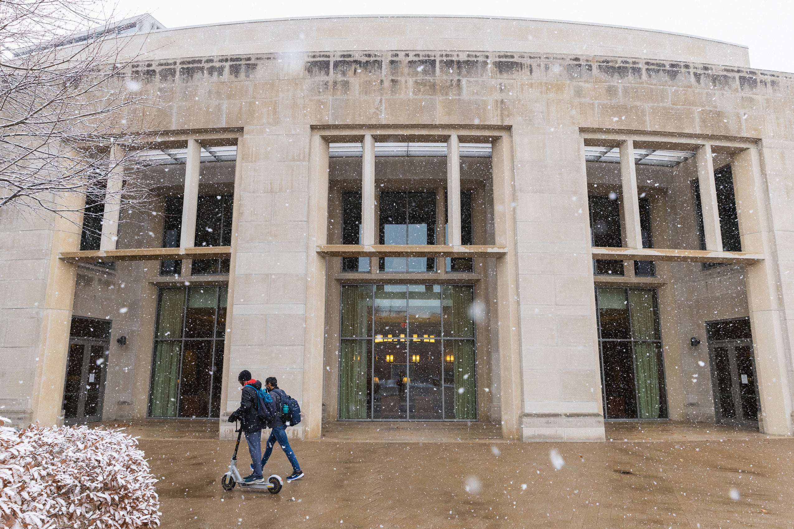 Two people walk by the WCC on the law school campus on a snowy day.