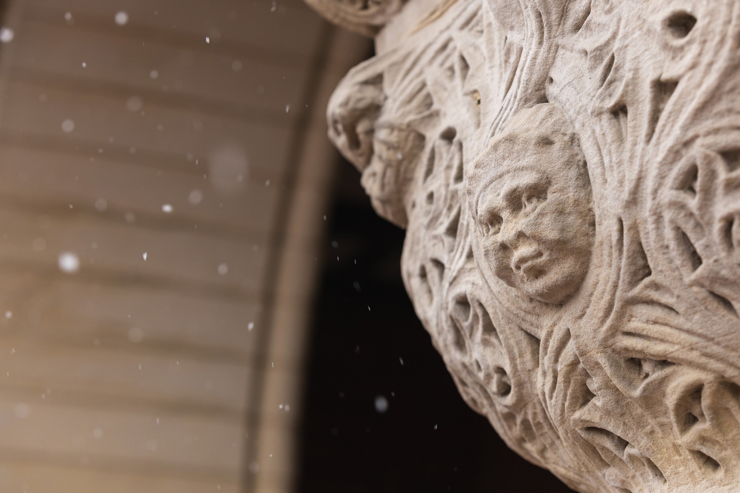 The architectural detail of a face on a building column on a snowy day.