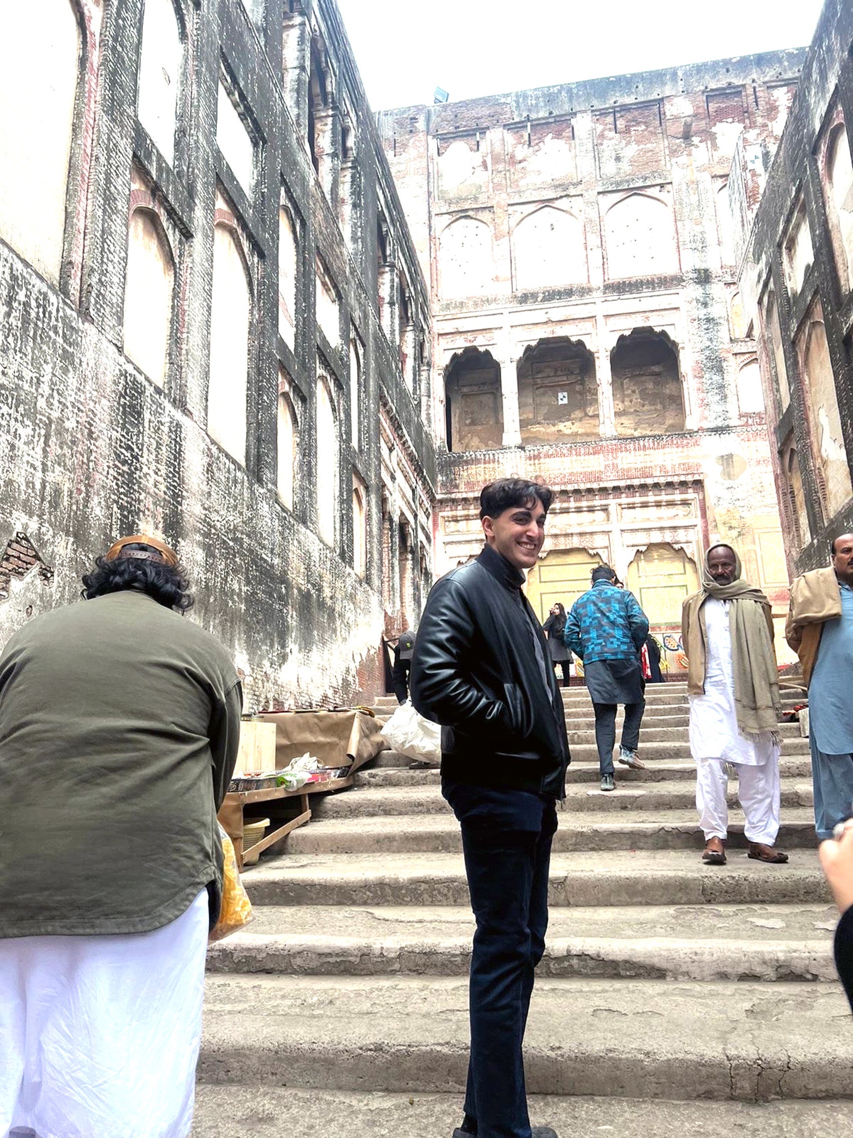 A man stands in the middle of a cement set of stairs as people pass by.