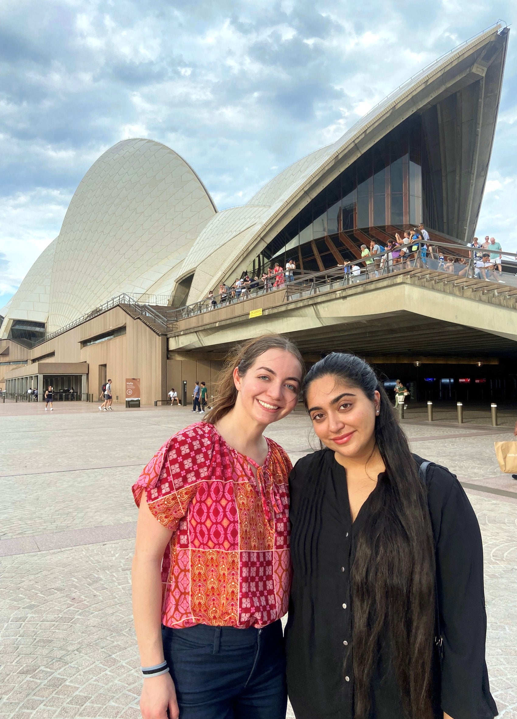 Two women stand in front of an opera house in Australia