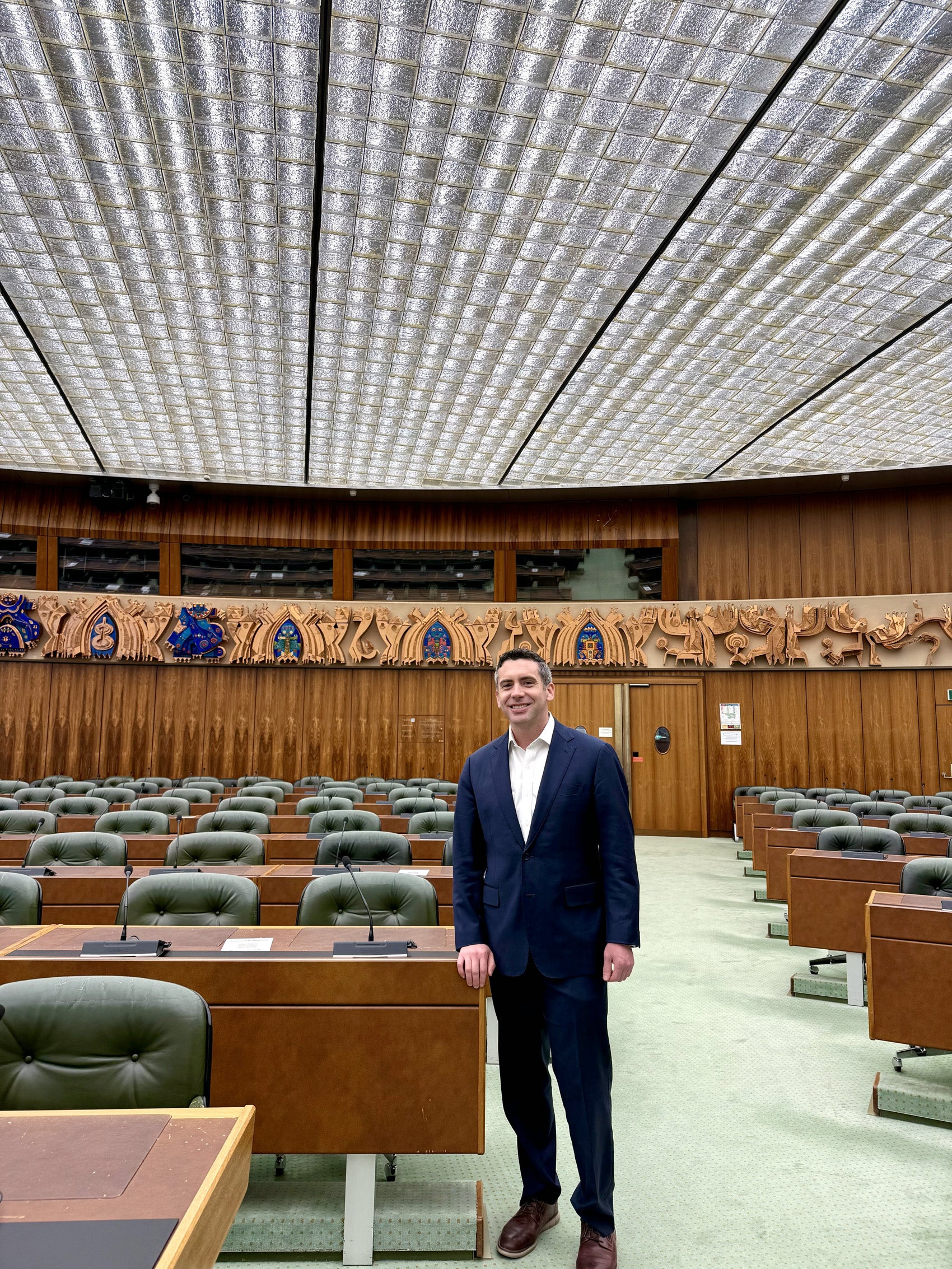 A man stand near some seating in a large room.