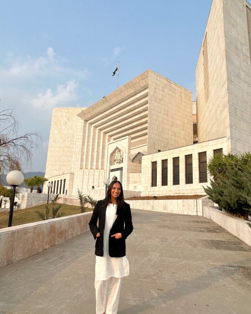 a woman stands in front of the Supreme Court of Pakistan