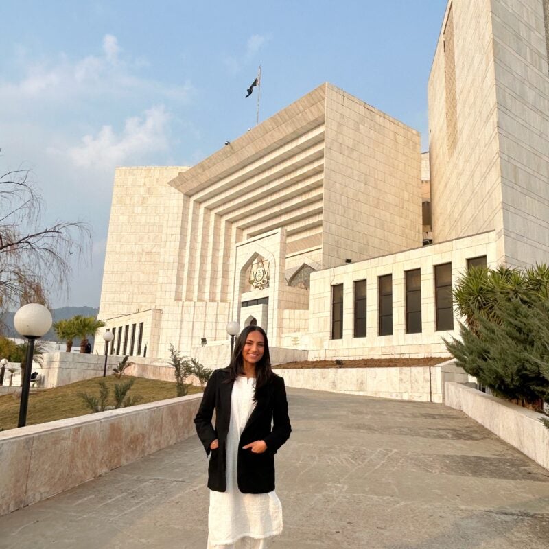 a woman stands in front of the Supreme Court of Pakistan