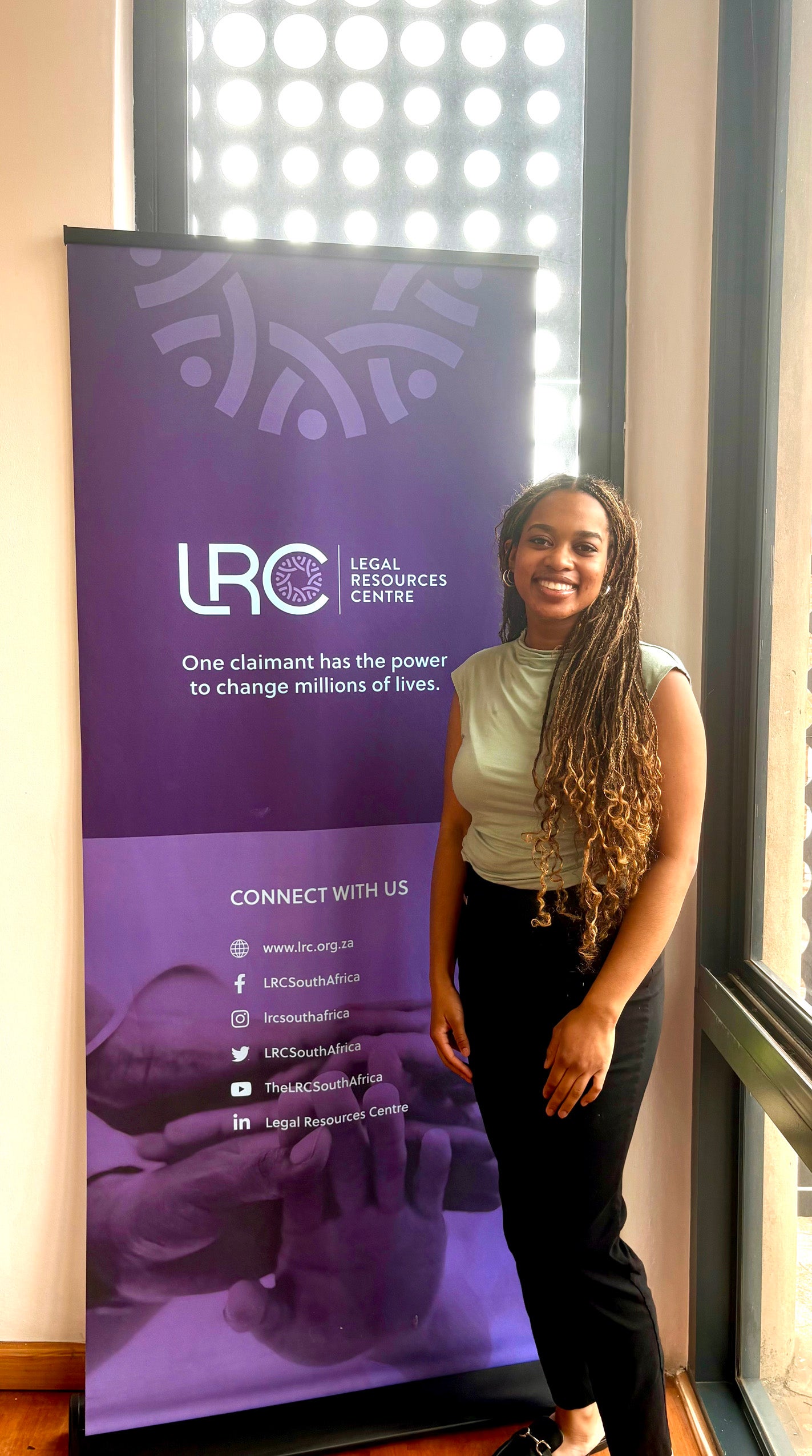 A woman poses in front of a sign that says 