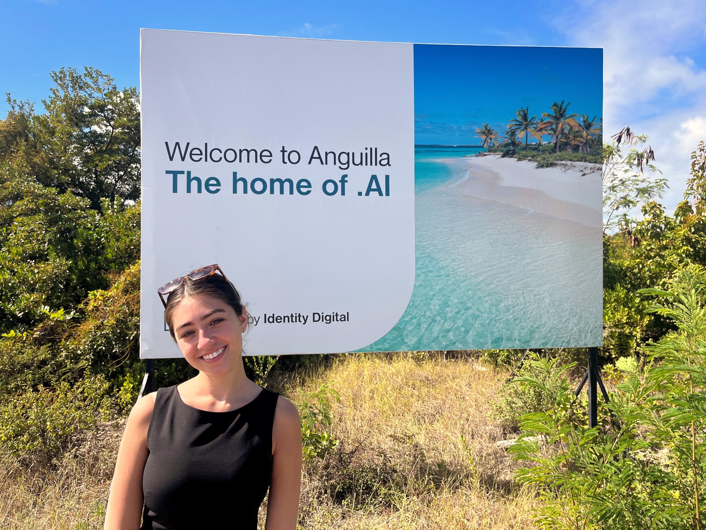 A woman stands in front of a sign that reads 